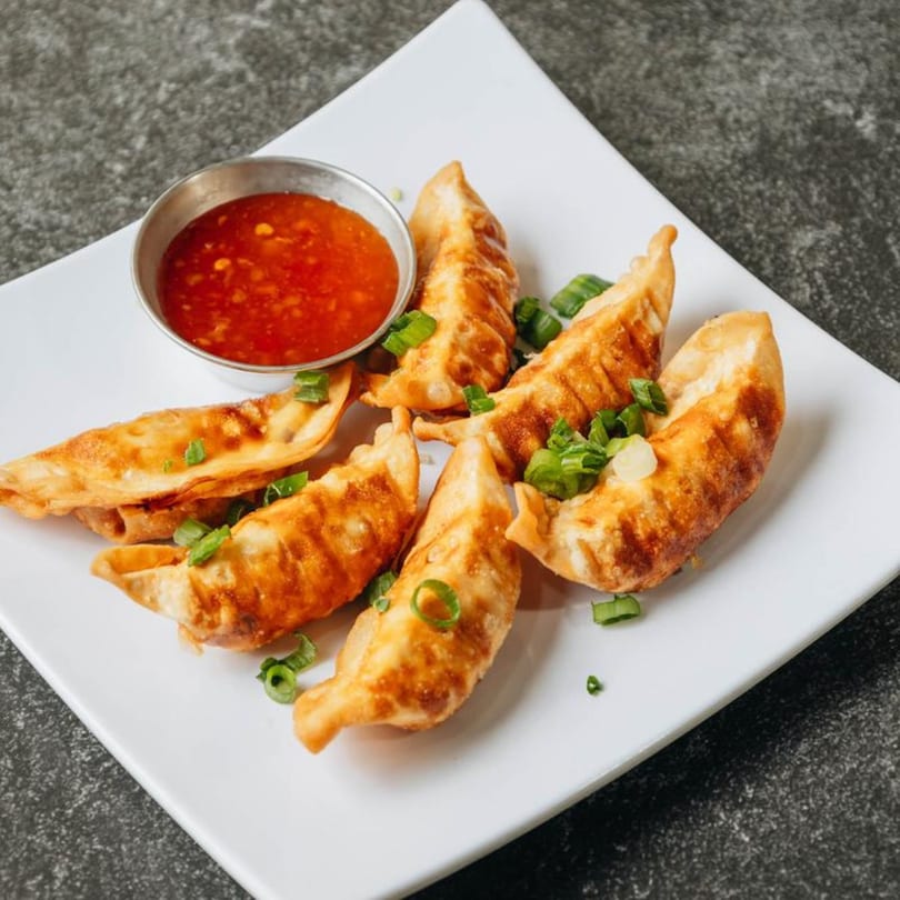 Crispy fried Filipino dumplings with green onions and a side of sweet chili dipping sauce.
